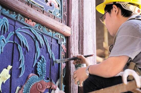 文物修缮工正在为木雕上色