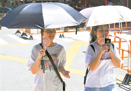 近期天气晴热,市民边撑伞遮阳边吹电扇   羊城晚报记者 王磊